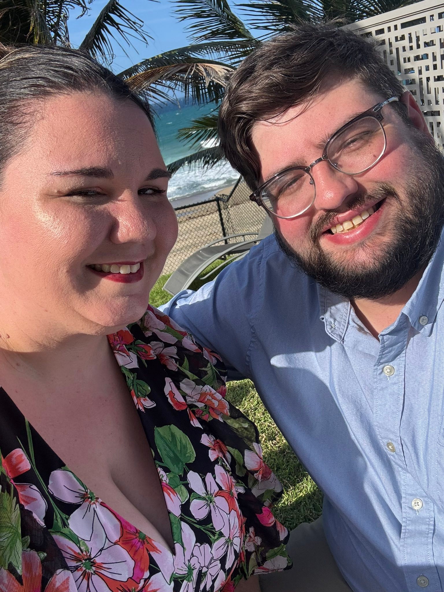 Ashley and Robert smiling together by the beach.